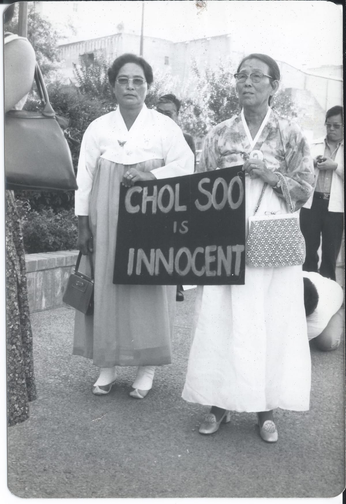 Two elderly Korean women wearing traditional dresses hold a sign that reads Chol Soo is innocent at a demonstration. Credit: Courtesy of Gail Whang.